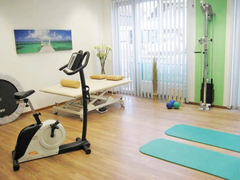 Heller Übungsraum mit Ergometer, Liege und Matten
